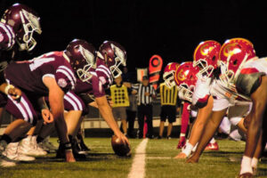 American football match with referee in the background on center line.